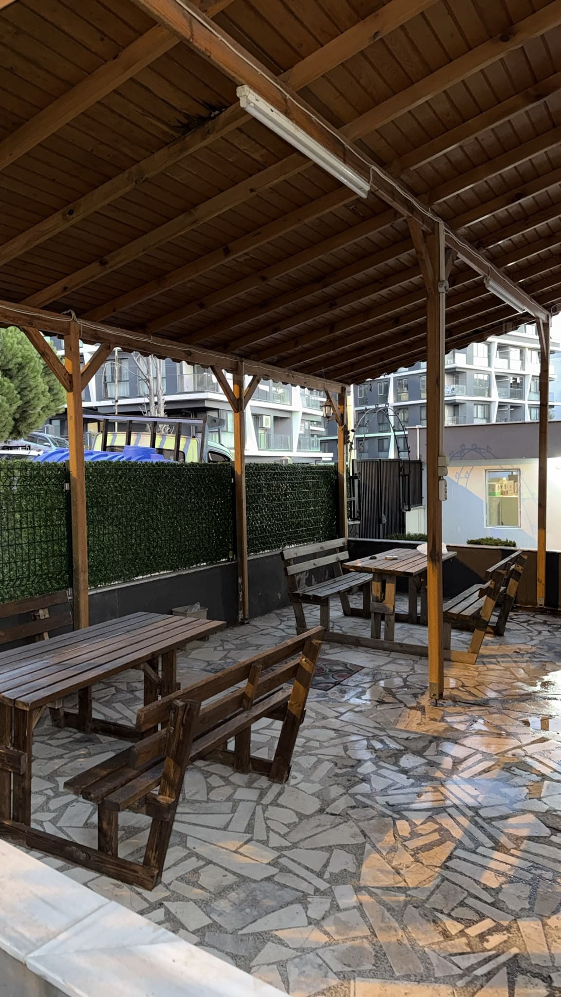 Çanakkale Kız Apart ortak bahçe oturma alanı, ahşap pergola altında masa ve banklar
