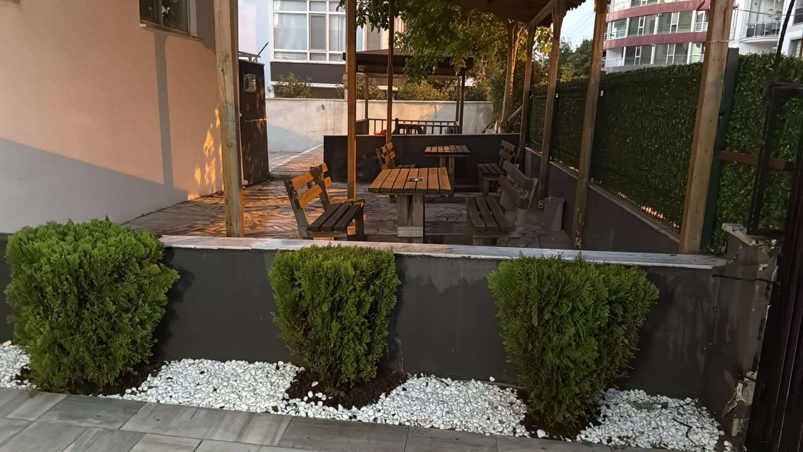 Çanakkale Kız Apart bahçesi, peyzajlı oturma alanı ve ahşap masalar